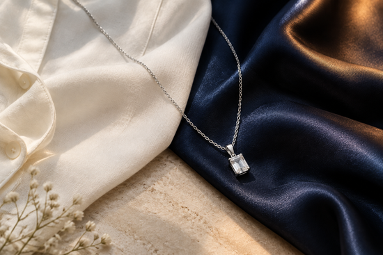 Illustrative silver-tone gemstone necklace across ivory daytime fabric and navy evening satin.