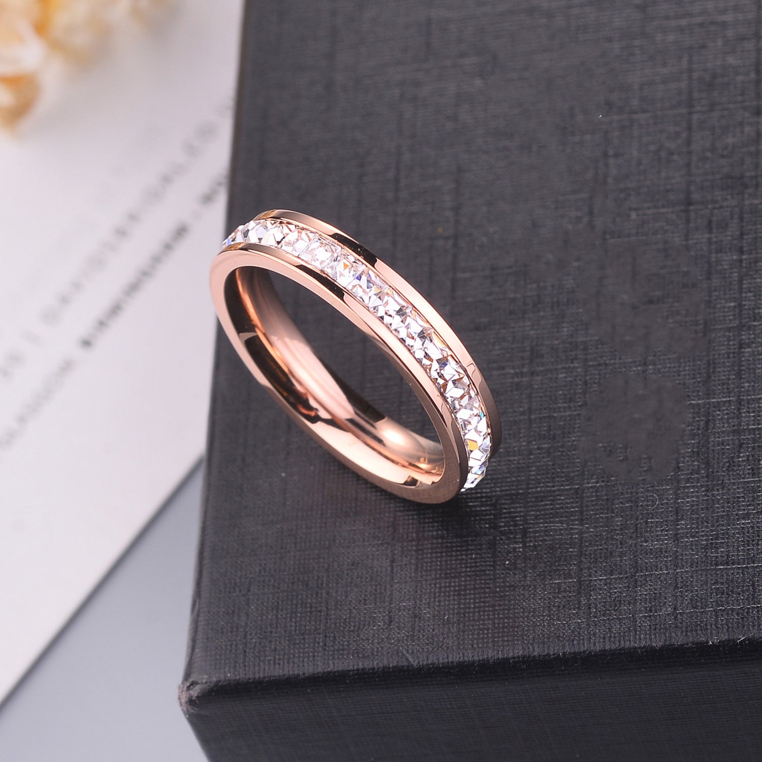 Minimal Titanium Rings For Women featuring a rose gold band with sparkling crystals on a black background.