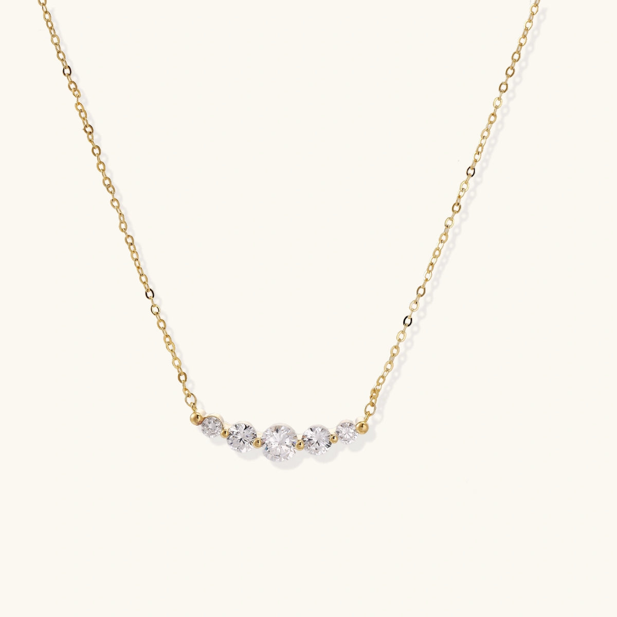 Delicate 14K gold-plated necklace with five graduated zirconia stones arranged in a curved arc on fine chain