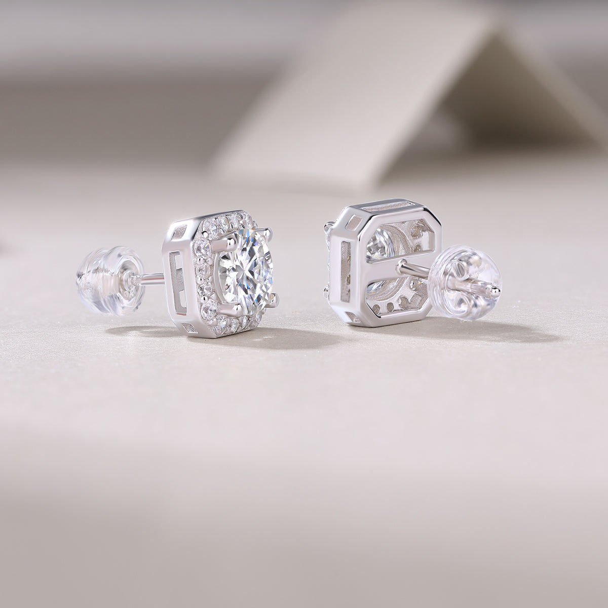 1Heart luxury moissanite diamond stud earrings set with silver ornaments on a light background.