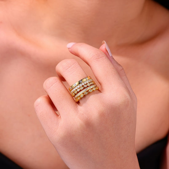 Moissanite wedding ring set displayed on a finger, featuring gold-plated bands with sparkling gemstones.