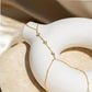 Gold hand chain bracelet with delicate beaded design displayed on a minimalist clay sculpture.