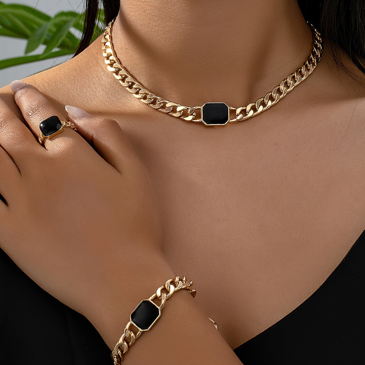 Luxury jewelry gift card featuring a stylish gold chain necklace, bracelet, and ring with black accents.