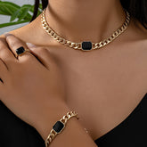 Luxury jewelry gift card featuring a stylish gold chain necklace, bracelet, and ring with black accents.