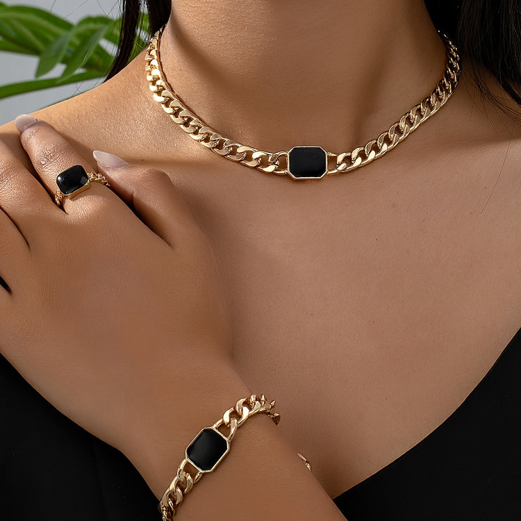 Luxury jewelry gift card featuring a stylish gold chain necklace, bracelet, and ring with black accents.